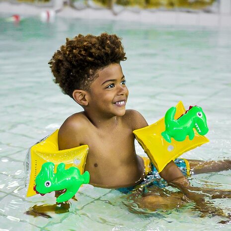 Kind in zwembad met dino zwembandjes